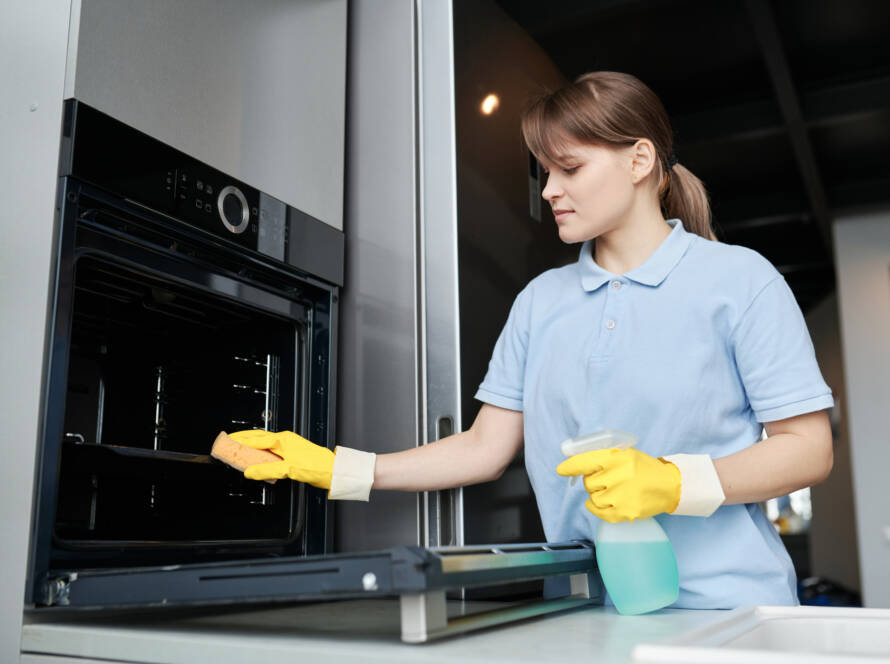 Mujer limpiando el horno en la cocina